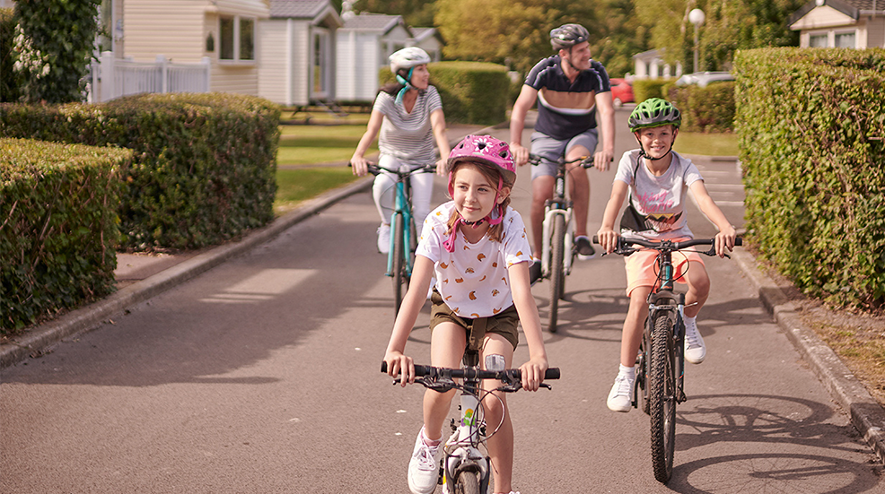 A family of four happily cycling through a Hoseason resort